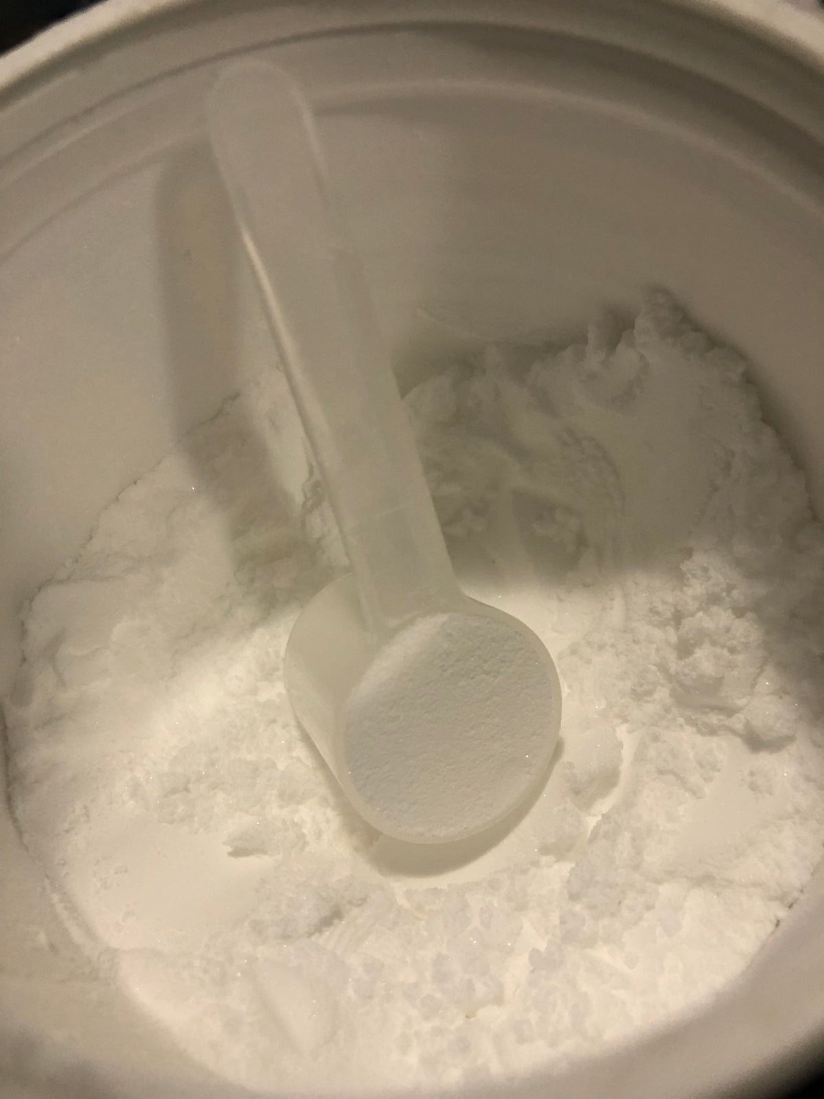 A close-up of white creatine monohydrate powder in a scoop